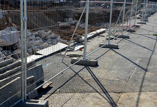 a temporary perimeter fence made with portable panels and sandbags